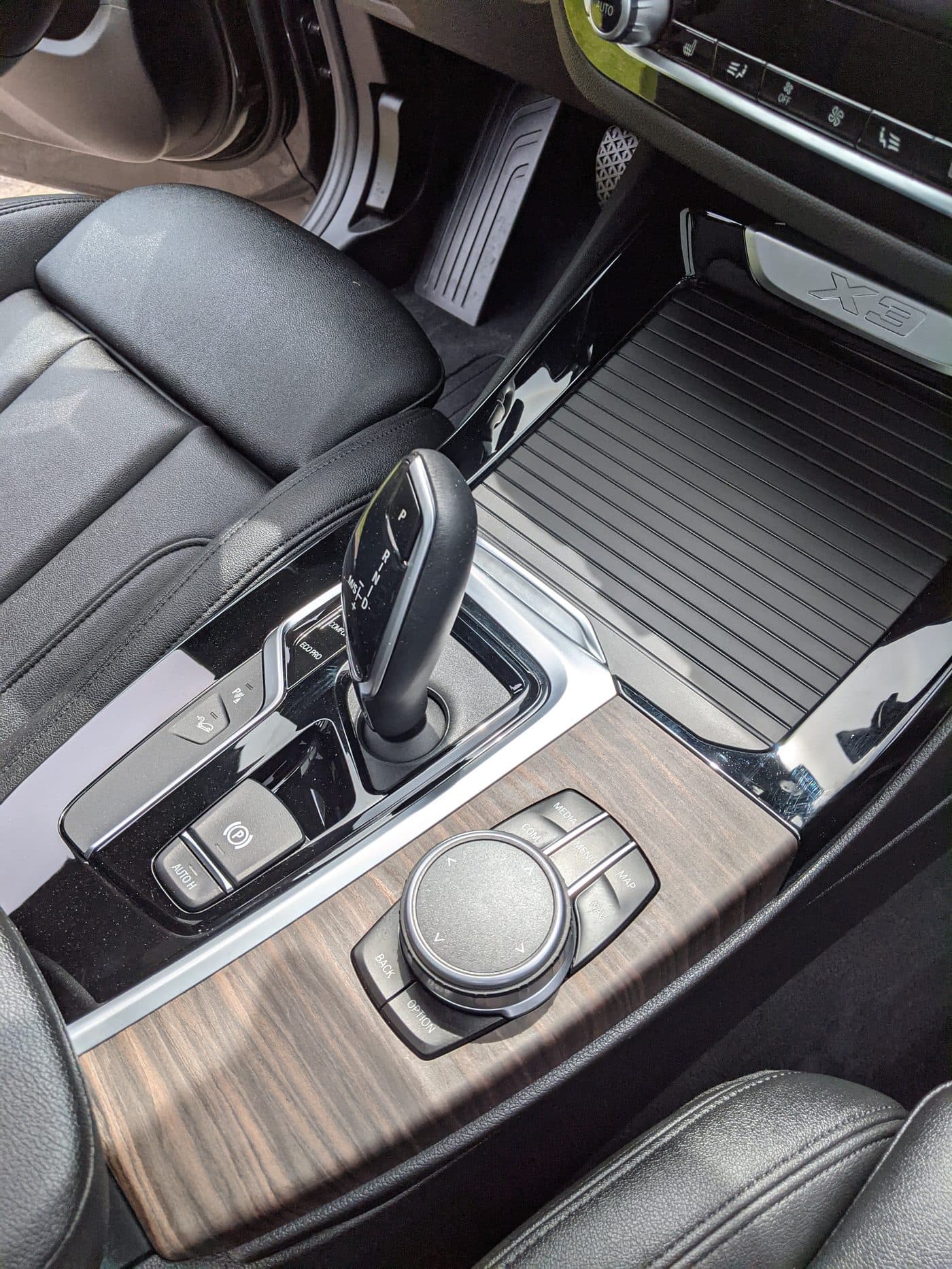 The centre console of a BMW X3 after an interior detail, wood trim and chrome cleaned and the gear selector surround free of dust