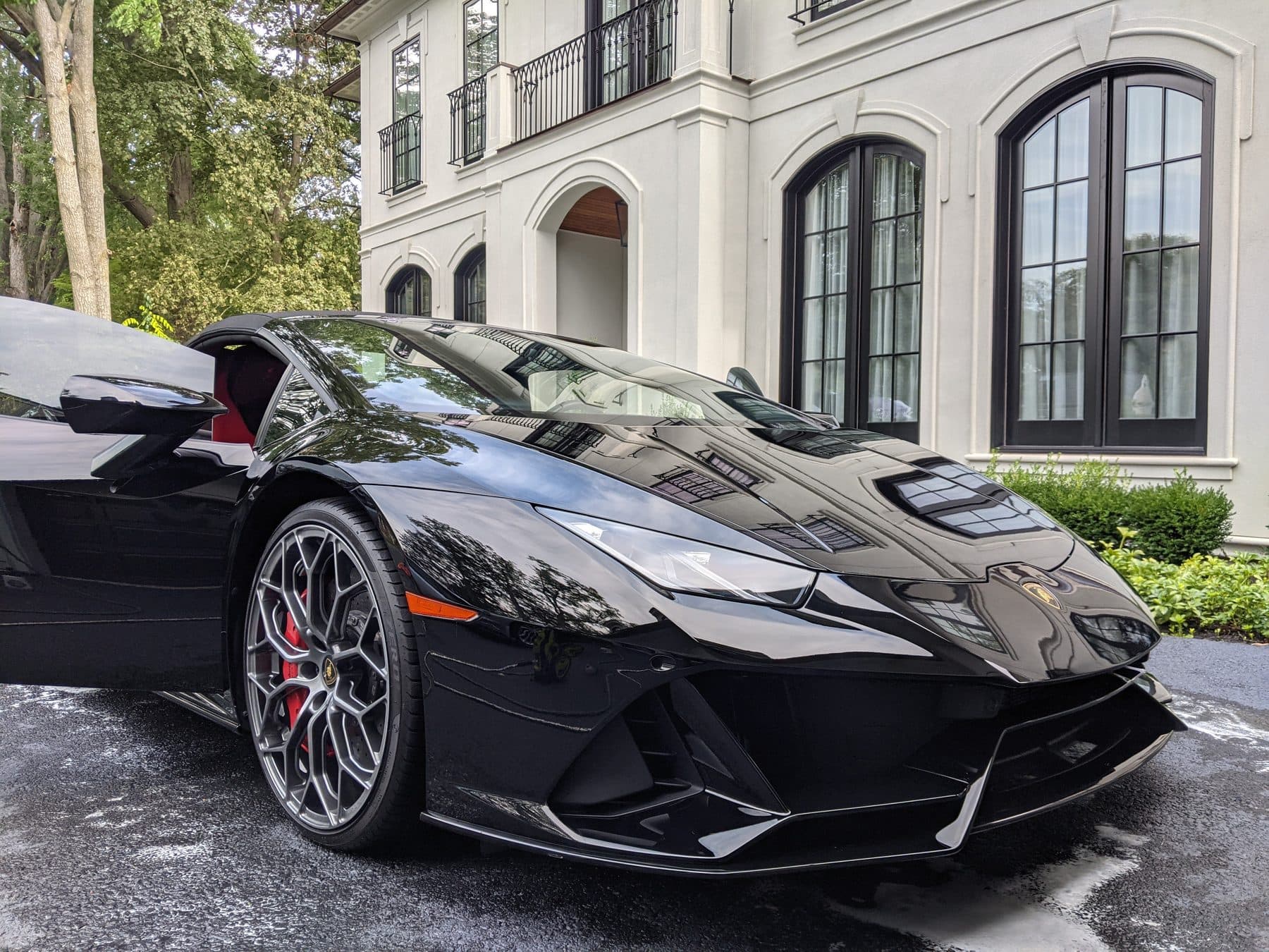 A black Lamborghini Huracan finished after a full detail, paint reflecting the house behind it